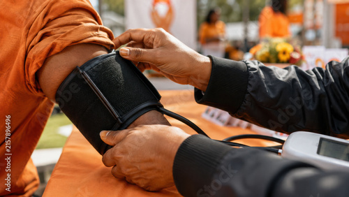 World stroke day. Close-up of a health volunteer hands checking a blood pressure cuff on a community member's arm. Stroke prevention screening event concept.
