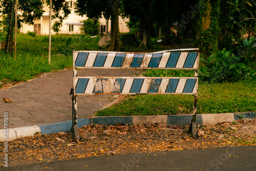 Worn road barricade by park path