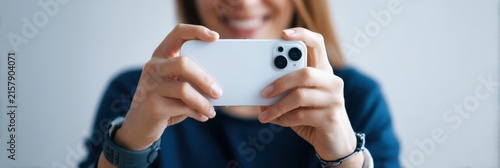 Woman hands hold smartphone taking photo or video stream. Smiling Asian photographer taking photo with cell phone, looking camera. Person holding smart phone. Social media content creation, selfie