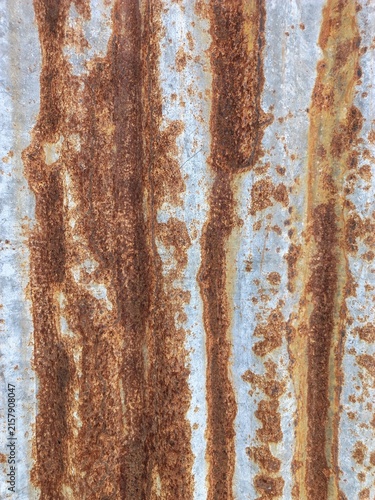 Rusted corrugated metal sheet showing weathered zinc surface with vertical orange corrosion streaks