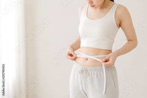Obraz na płótnie メジャーでウエストを測定する女性のダイエットや体重管理と健康管理のイメージ
