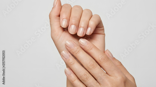 Hands showing clean natural fingernails with a soft glossy finish on a white background for minimalist manicure and nail care content