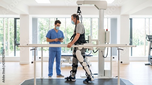 Patient uses exoskeleton robotic suit for physical therapy with medical professional supervision