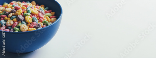Ciotola in ceramica blu con bocconcini di cereali alla frutta in primo piano su una superficie bianca con spazio per testo - formato panoramico