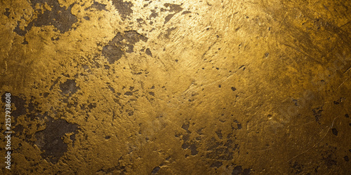 Textured gold surface with dark patina in dramatic studio lighting for luxury backgrounds