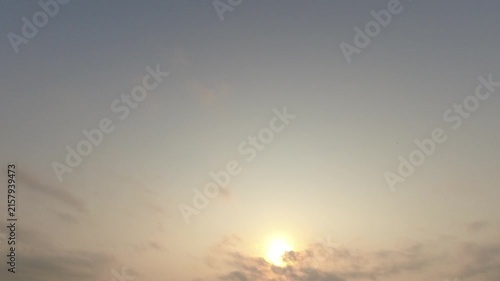 Beautiful sunrise sky with a silhouette of a bird flying across the frame. Glowing sun and hazy clouds in a peaceful morning nature background.