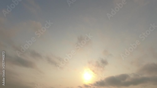 Cinematic timelapse of the sun setting with soft clouds passing by. Warm glowing twilight sky atmosphere perfect for nature backgrounds.