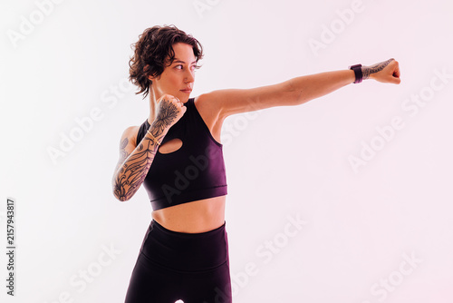 Slim woman in black fitness wear practicing shadow punches in a studio