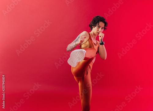 Woman in golden fitness attire kicking her leg towards the camera