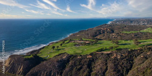 Aerial view of Torrey Pines Golf Course featuring lush green fairways and sand bunkers situated on coastal cliffs overlooking the Pacific Ocean in San Diego, California, United States.