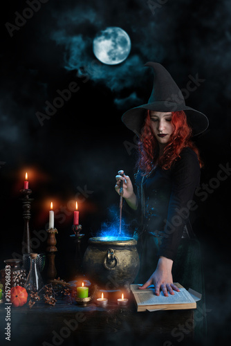Obraz na płótnie Witch with magic wand casts spell, cauldron, boiling magic potion, candles