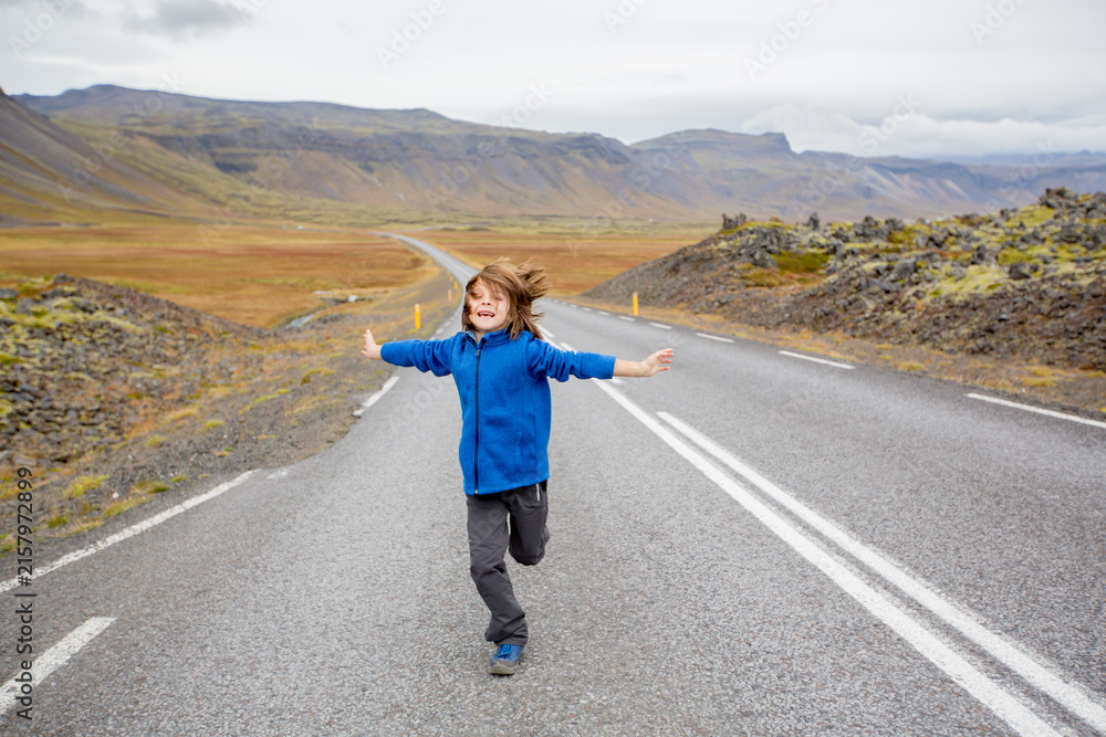 Fototapeta premium Child, playing on a road near non active vulcano in Snaefellsjokull National Park, Iceland autumntime