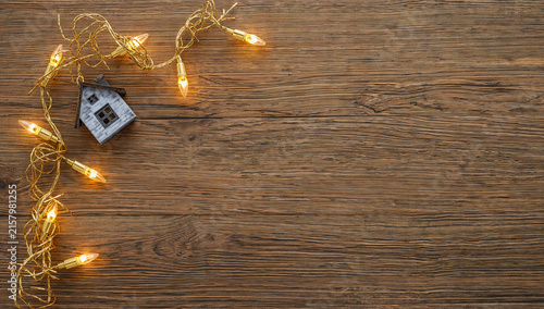 Decorative house with warm garland lights on wood
