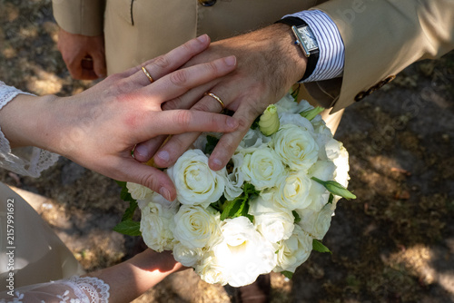 Obraz na plátne Mains de jeunes mariés montrant leurs alliances au-dessus du bouquet de mariage