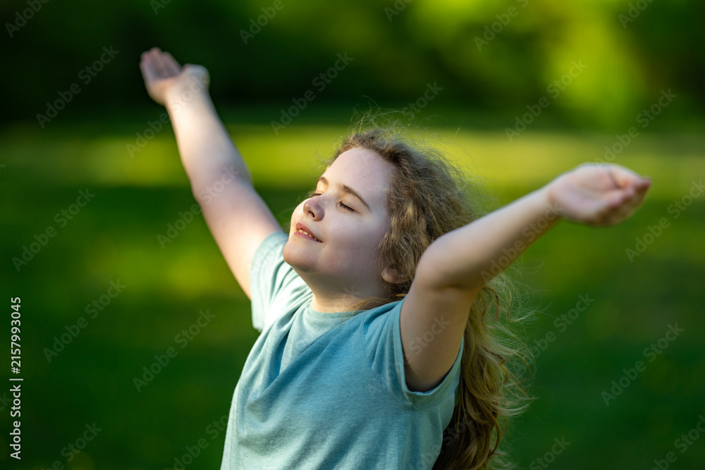 Naklejka premium Carefree child enjoys summer meadow. Carefree childhood feels peaceful outdoors. Happy carefree kid opens arms. Natural carefree joy fills field.