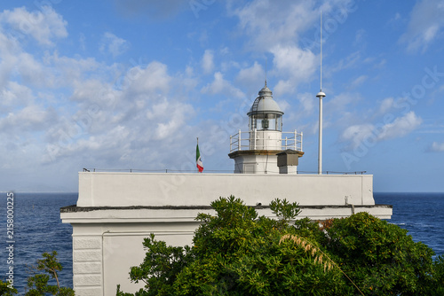 Bild auf Leinwand Scenic view of the historic Portofino lighthouse with the Italian flag under a c