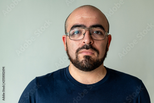 Foto Man with glasses and beard wearing a dark shirt against a plain background