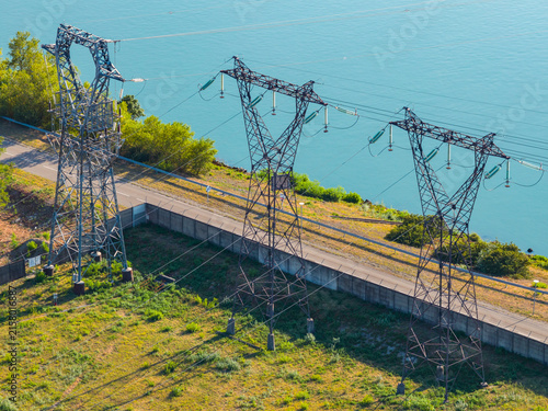 Aerial view of high voltage transmission towers and power lines near a river in Saulce-sur-Rhone, Auvergne-Rhone-Alpes, France.