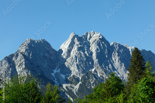 Travel landscape of Zugspitze Alps in Bavaria, Germany, scenic summer nature panorama with forest, snow mountains peak. Alpine landscape