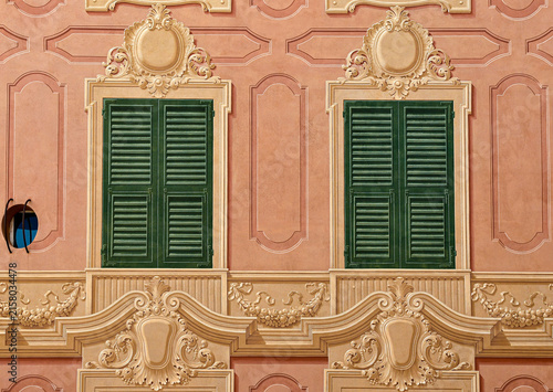 Symmetrical pattern of traditional Ligurian trompe l oeil painted windows on a pink facade in Genoa, Liguria, Italy