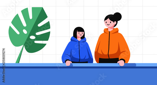 Two happy girls wearing hoodies standing in front of a tiled wall