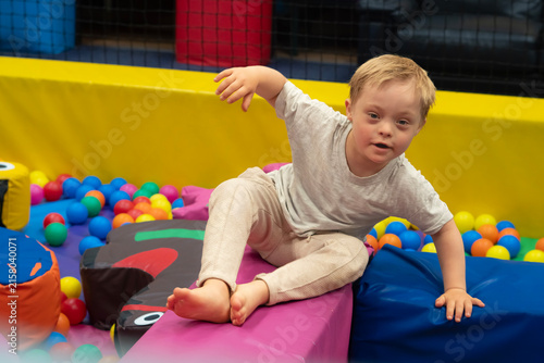 Obraz na płótnie Boy with Down Syndrome Playing in Colorful Indoor Soft Play Area