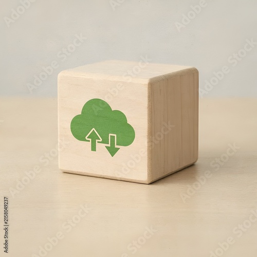 Wooden cube with green cloud and arrows symbol indicating cloud computing and data transfer.