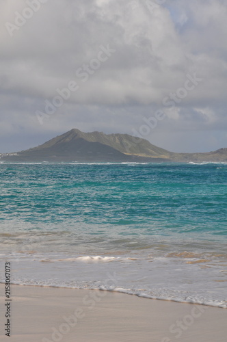 Sandy Hawaiin beach with clouds and mountain in background
