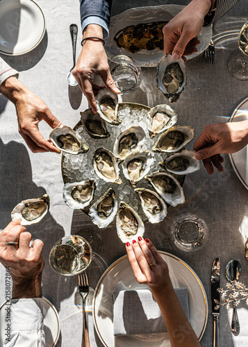 Friends sharing a large platter of fresh raw oysters at a restaurant