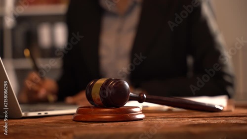 Gavel of Justice: A judge's gavel rests on a wooden desk, with a legal professional in the background diligently working, embodying the essence of law and order.