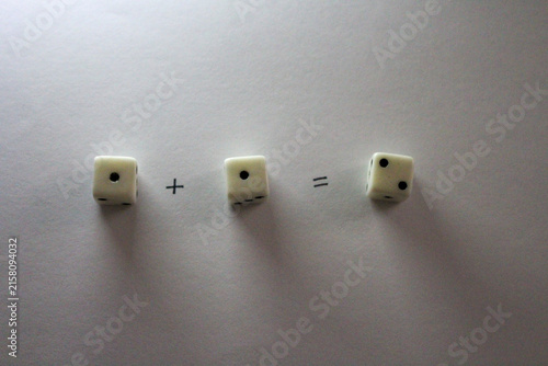 Fotografie An addition math problem shows white dice — displaying numbers via their dots — on a white background, casting shadows