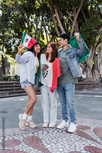 young Mexican people with flags to celebrate mexican independence day and cheering Viva Mexico 