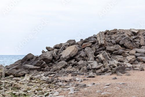 Foto Large rock formation on a sandy beach with ocean waves gently lapping at the sho