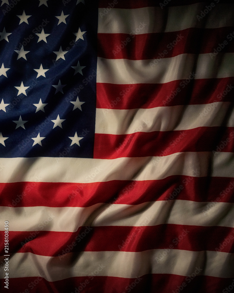 Obraz premium Close up of waving American flag fabric with stars and stripes, dramatic folds and textured surface creating a patriotic vertical background.