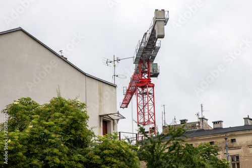 Принти на полотні Luffing jib tower crane, positioned tightly between urban buildings, its movable angled steeply upward to operate within confined airspace constraints
