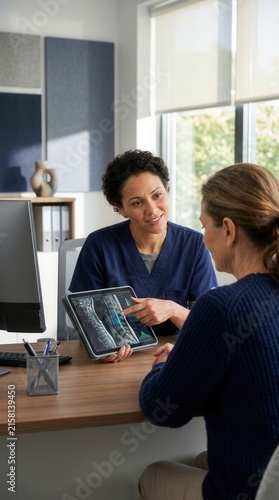 Doctor Explaining Medical Scan Results To Patient On Digital Tablet