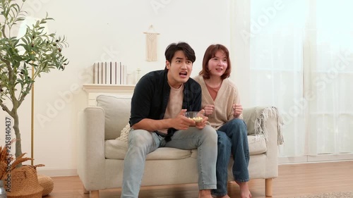 Fans Celebrate Football Win While Watching on Couch at Home During Evening Hours With Snacks