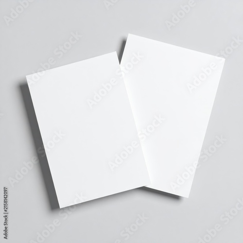 two blank paper sheets on a gray background