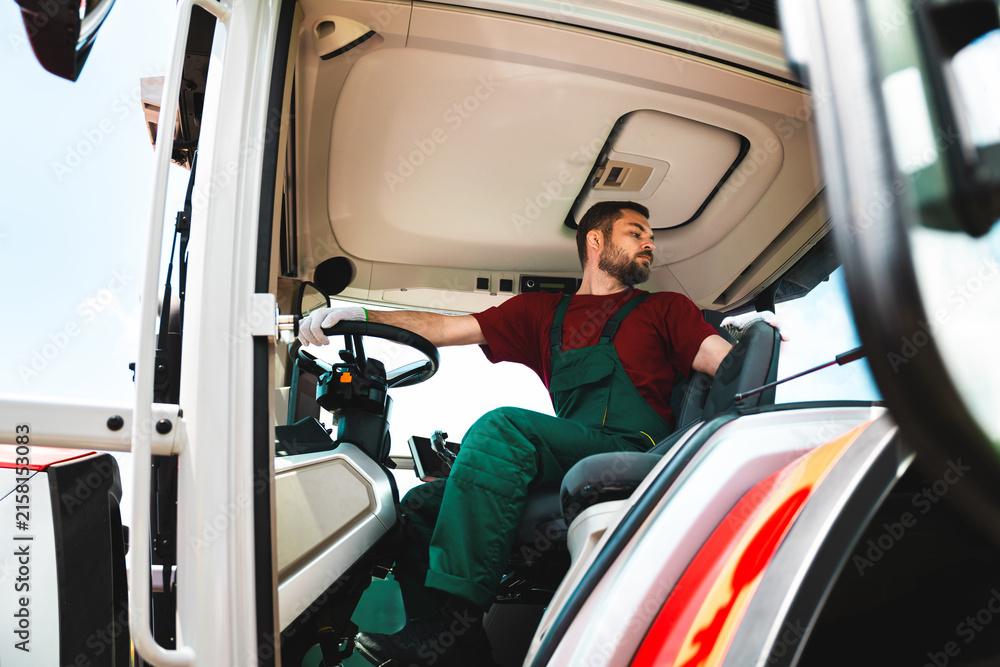 Naklejka premium Adult man wearing workwear operating a tractor.