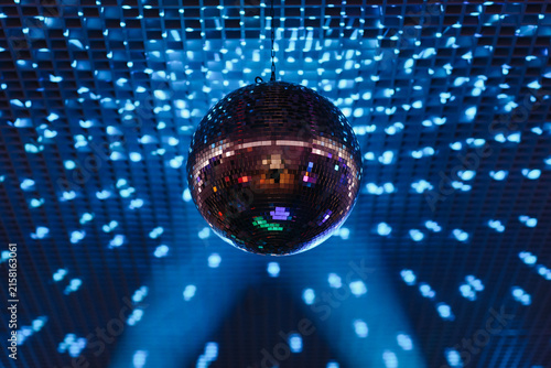 disco ball with mirror surface and bright rays, blue light, hanging on ceiling, night party background