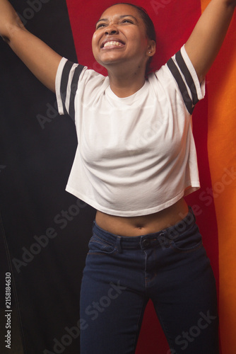 Woman posing in studio with colorful panels, wearing striped cropped tee and dark jeans