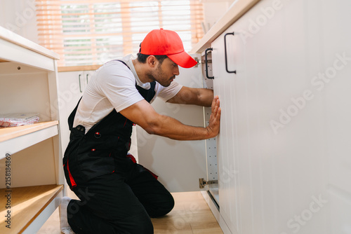 Professional Technician Adjusting Kitchen Cabinet During Home Installation Ensuring Quality Service