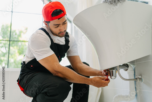 Professional Plumber Fixing Sink Pipe in Modern Bathroom for Residential Maintenance Services