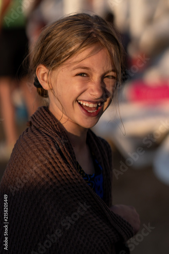 Adorable girl wrapped in towel after swimming at tropical beach. 