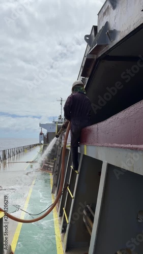 crew washing coaming of ship cargo hold.