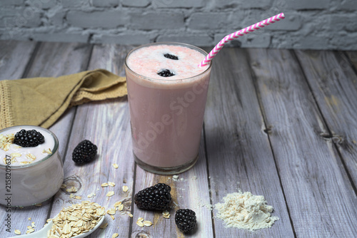 Strawberry smoothie with blackberries protein powder oat flakes and yogurt on wooden background for healthy nutrition concept