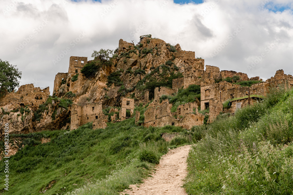 Fototapeta premium Deserted mountain settlement rests among rugged peaks and wild greenery