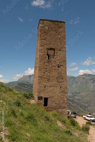 Ancient stone tower rises tall amid mountainous landscape under blue sky