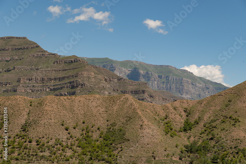 Rolling green hills rise beneath a bright blue sky