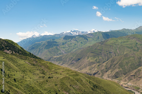 Majestic snow-capped mountains rise above rolling green hills